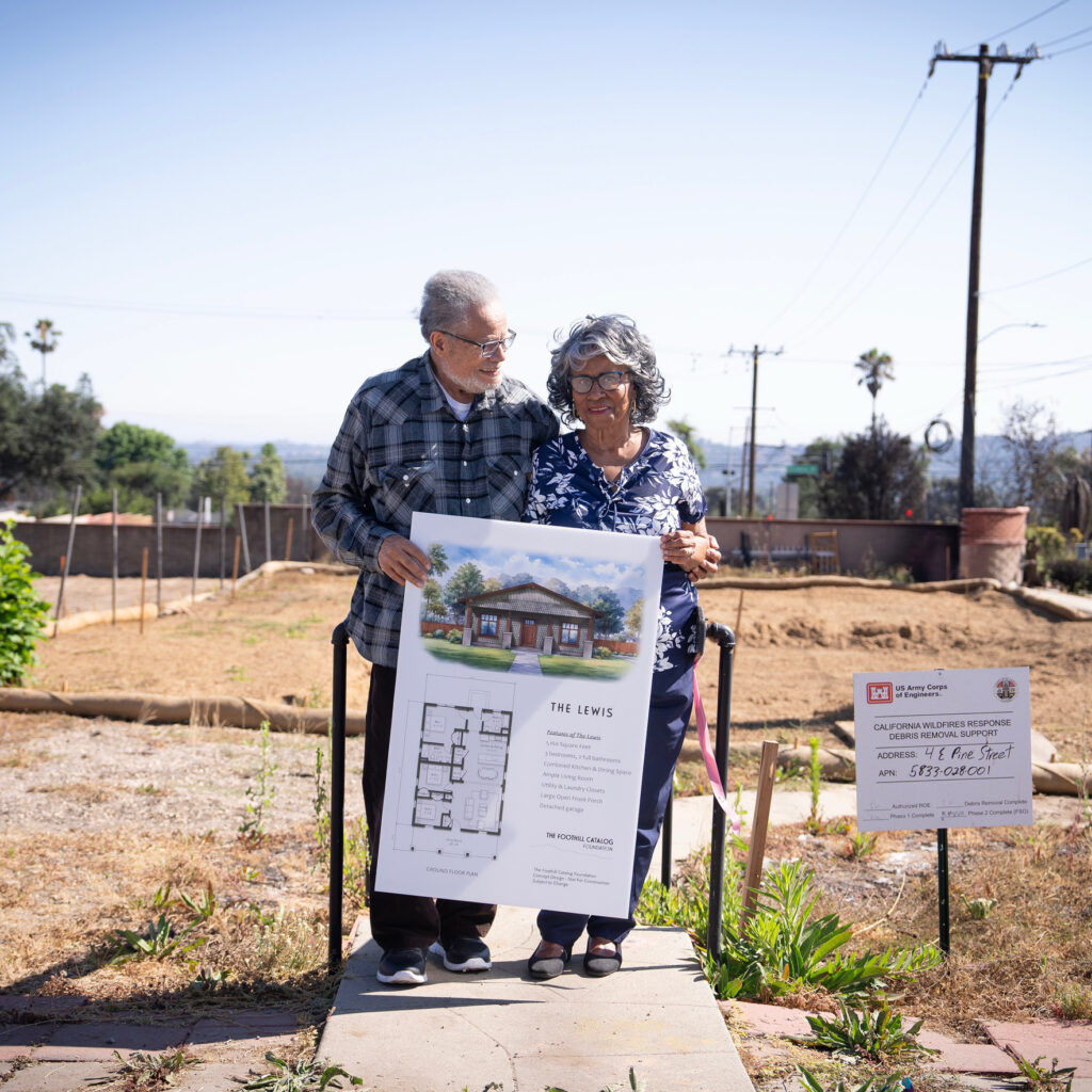 Homeowners in front of a lot, holding their building permit.